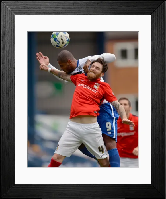 Framed Print : Clash at Gigg Lane: A Battle Between Leon Clarke and Romain Vincelot in Sky Bet League One