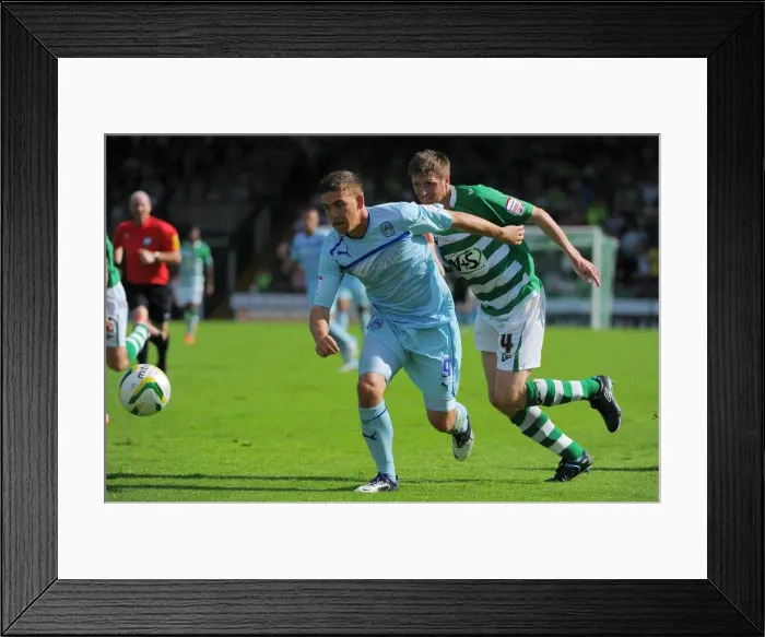 Framed Print : Cody McDonald's Determined Goal: Overcoming Richard Hinds in Coventry City's Victory at Huish Park (August 18, 2012)