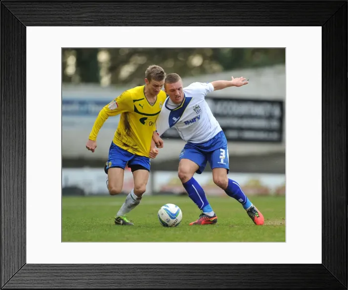 Framed Print : Battling for Control: Carl Baker vs. Joe Skarz in Npower League One Clash at Gigg Lane Framed Print : Battling for Control: Carl Baker vs. Joe Skarz in Npower League One Clash at Gigg Lane