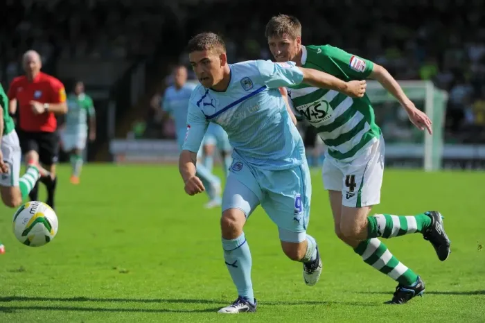 Framed Print : Cody McDonald's Determined Goal: Overcoming Richard Hinds in Coventry City's Victory at Huish Park (August 18, 2012)