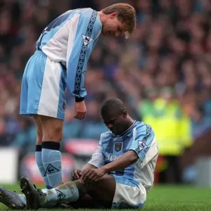 Comfort and Care: Roland Nilsson Consoles Injured George Boateng on the Field (FA Carling Premiership: Aston Villa vs Coventry City, 1999) Comfort and Care: Roland Nilsson Consoles Injured George Boateng on the Field (FA Carling Premiership: Aston Villa vs Coventry City, 1999)