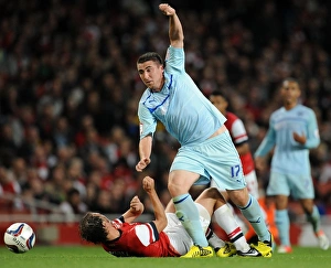 Prints of Coventry Citys Callum Ball (right) skips past Arsenals Ignasi Miquel during the Capital One Cup, Third Round match at the Emirates Stadium, London Capital One Cup Prints: Callum Ball Dodges Ignasi Miquel in Coventry City's Capital One Cup Showdown at Arsenal's Emirates Stadium
