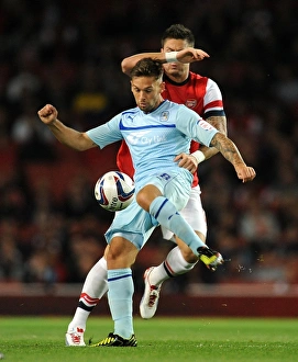 Prints of Coventry Citys James Bailey (left) in action with Arsenals Olivier Giroud during the Capital One Cup, Third Round match at the Emirates Stadium, London Capital One Cup Prints: Capital One Cup Showdown: A Clash of Stars - Bailey vs Giroud