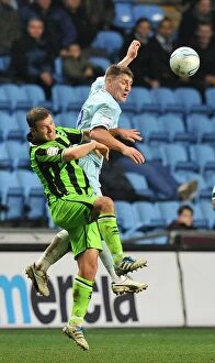 Images Dated 31st December 2011: Clash at Ricoh Arena: Footballers Leap for the Ball - Coventry City vs. Brighton & Hove Albion